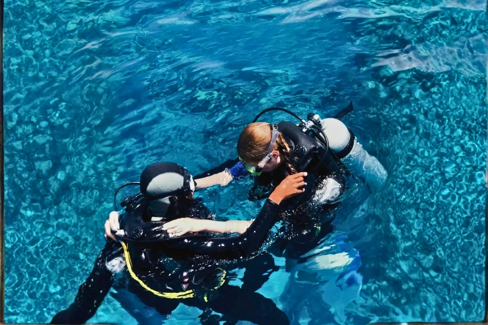 Scuba instructor guiding a student underwater in clear blue waters during a 6 day galapagos diving course in Ecuador