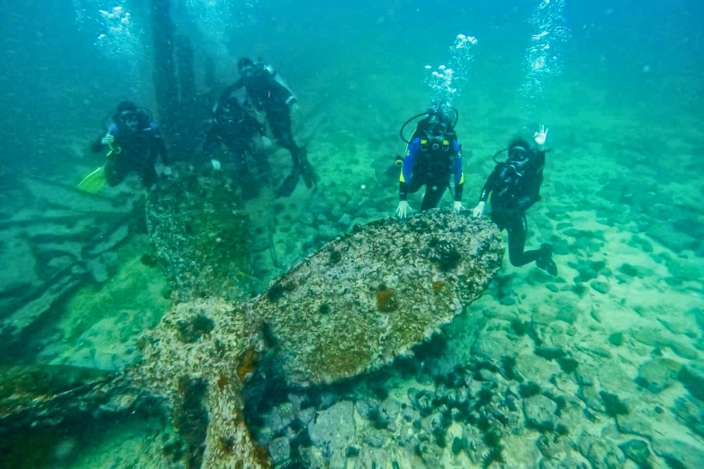 Scuba divers exploring the historic Carawa wreck during a padi open water galapagos dive off San Cristóbal Island