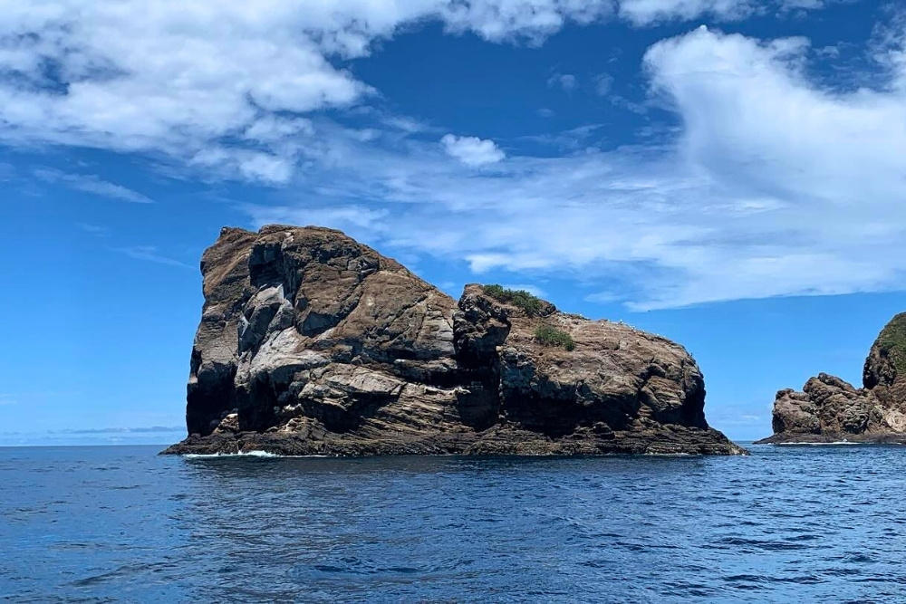 Massive volcanic rock formation rising from deep ocean waters at Gordon Rocks dive site in the Galapagos Islands
