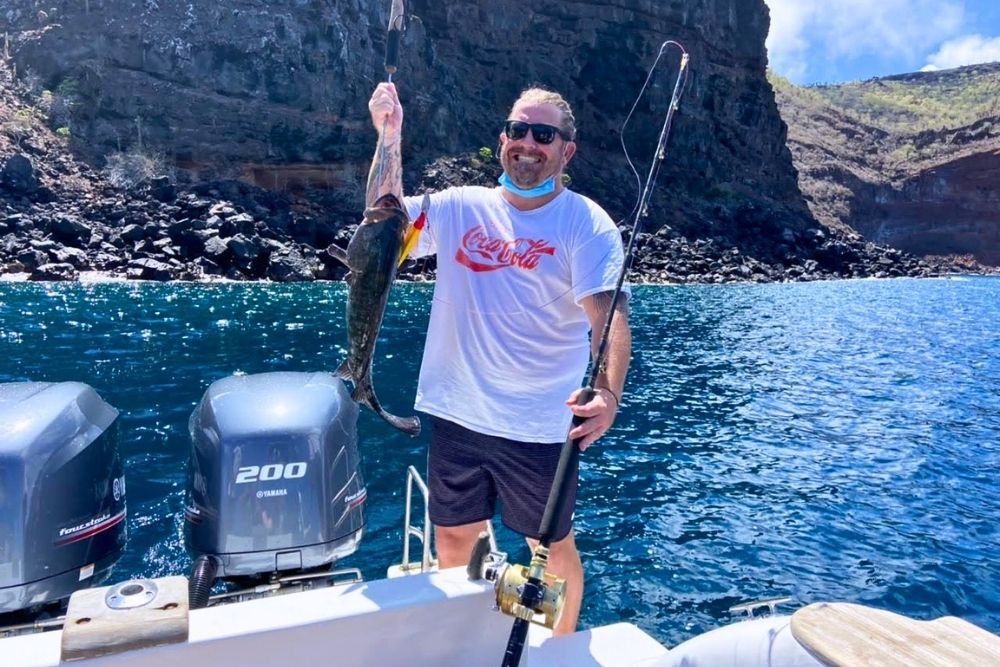 Happy angler holding up a fresh catch on a boat off Pinzon Island during an exciting Galapagos Fishing Tour excursion