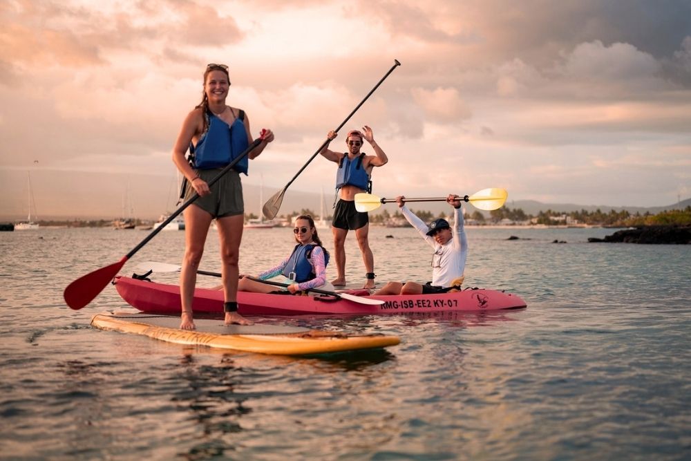 Group paddleboarding and kayaking in calm ocean waters off Puerto Villamil on an 8-day galapagos tour adventure