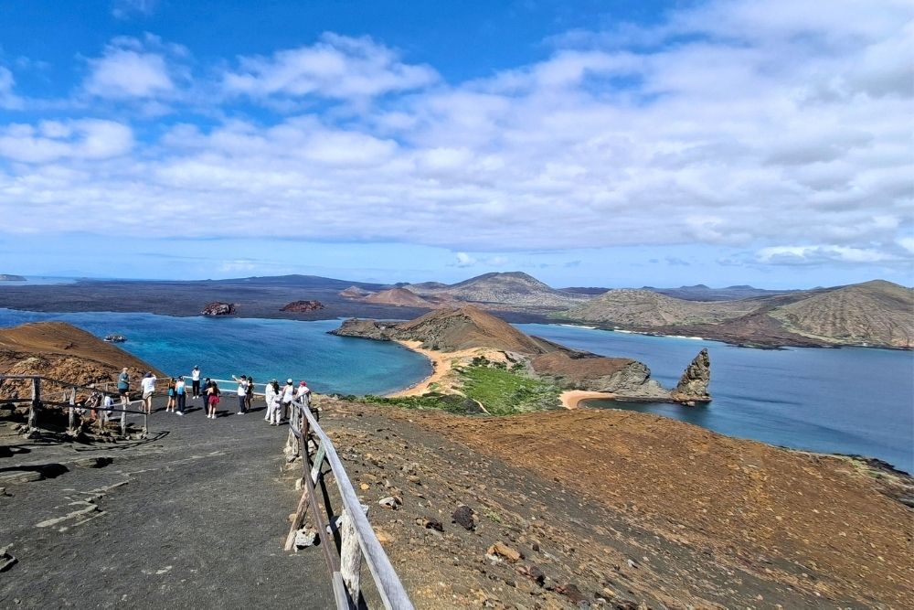 Tourists enjoying the iconic view of Pinnacle Rock on Bartolome Island during a Galapagos island hopping 8 days tour
