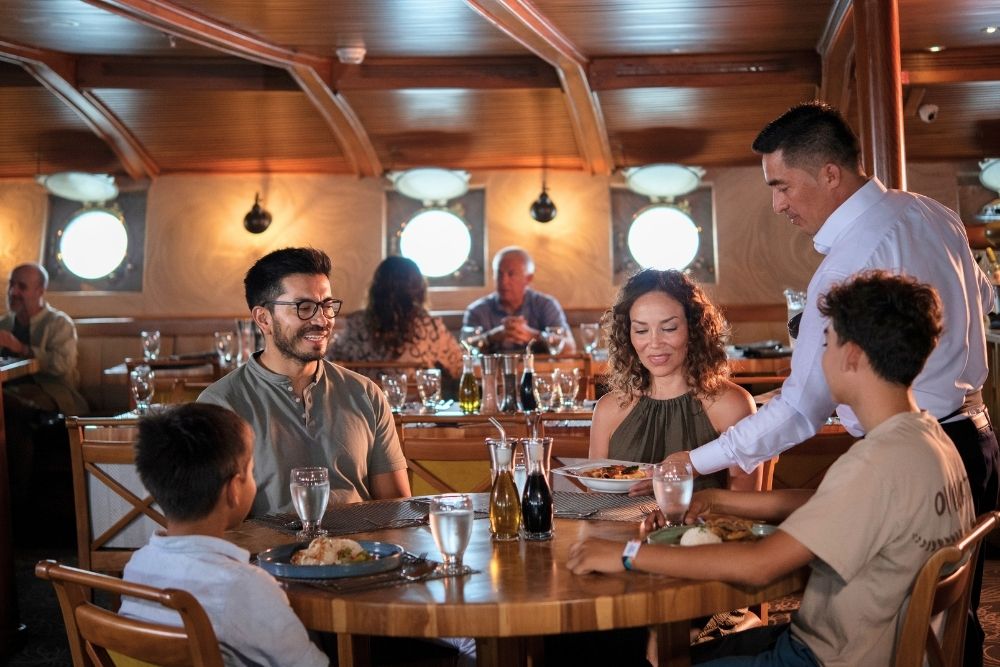 Family enjoying gourmet dining served aboard a luxury Galápagos cruise Ecuador vessel like the Galapagos Legend ship