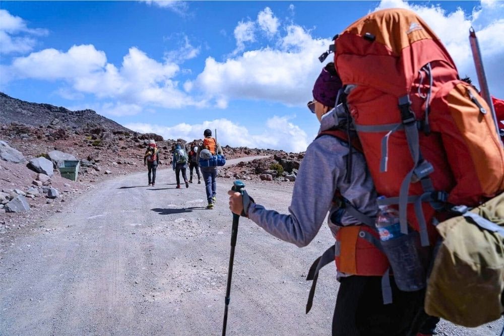 Hikers carrying heavy backpacks along a dusty gravel trail during a Chimborazo trek on a 3 weeks in Ecuador itinerary