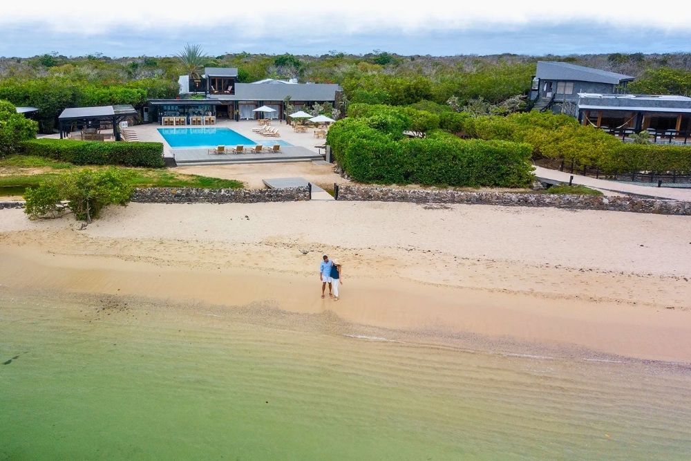 Aerial view of guests walking on the beachfront near the outdoor pool at Finch Bay during a luxury Galapagos tour
