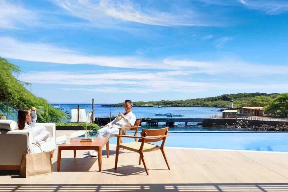 Guests relaxing by an infinity pool overlooking the bay at Hotel Indigo, one of the top Galapagos Luxury Hotels