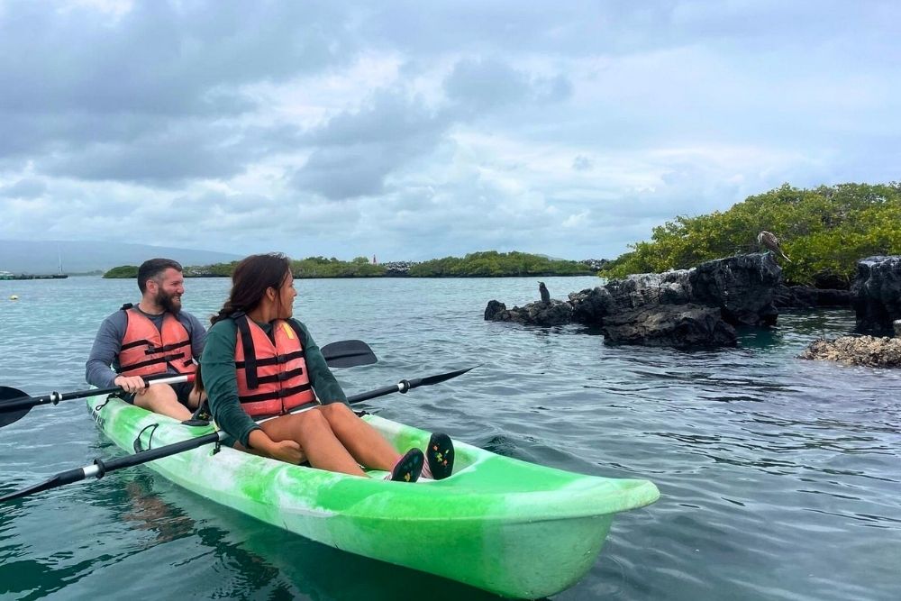 Couple kayaking near lava rocks and coastal wildlife during a Galapagos Safari excursion near Puerto Villamil in Isabela