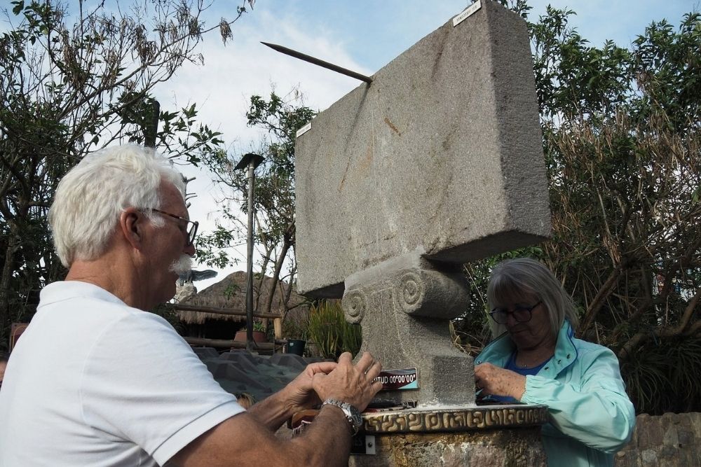 Tourists testing equatorial physics at a solar sundial monument at Intiñan Museum during an Ecuador grand tour