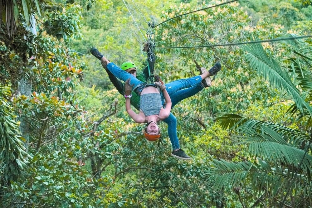 Thrilled tourist gliding upside down on a Mindo zipline adventure through cloud forest during a 23 day Ecuador tour