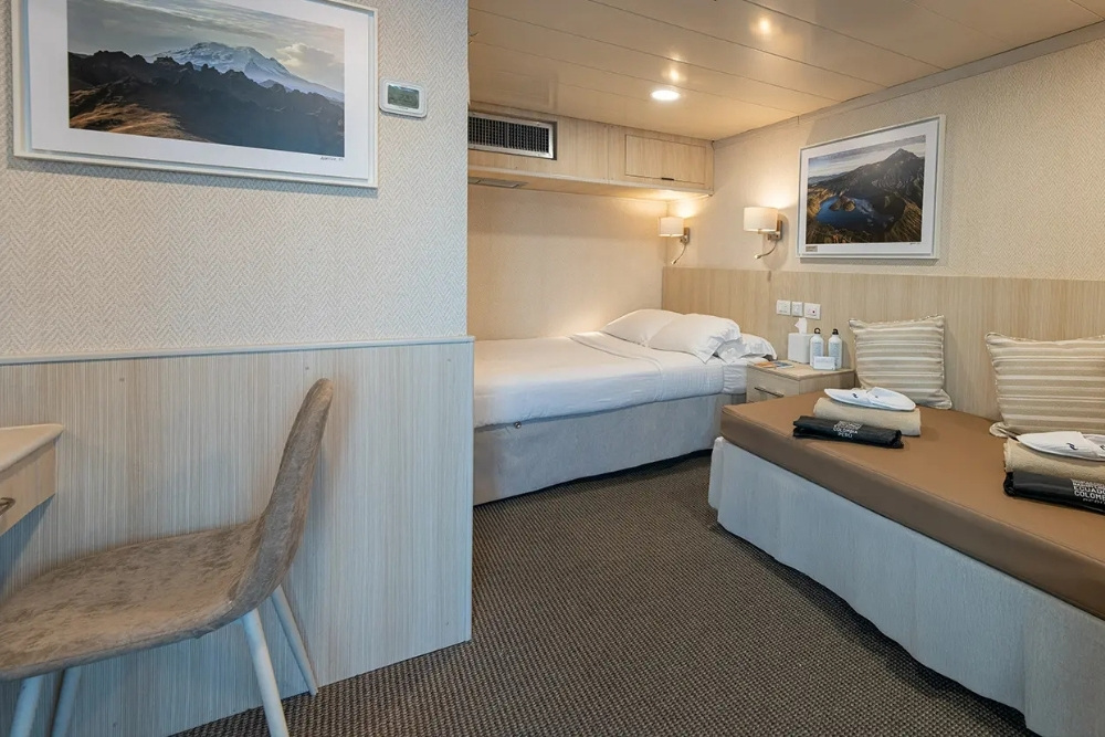 Triple cabin with lower beds and a comfortable seating area on an Isabela II Galapagos Cruise