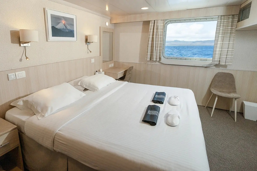Bright master suite featuring a large ocean-view window on an Isabela II Galapagos Cruise.