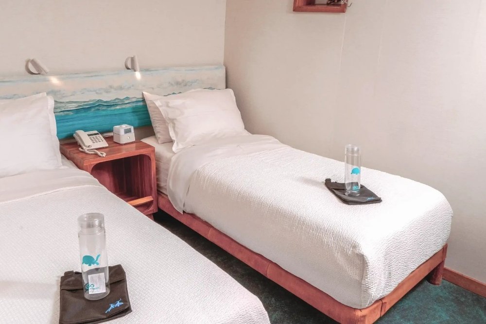a comfortable twin bed setup with wooden nightstands aboard the coral yachts.