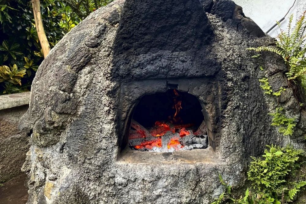 Wood-fired stone oven burning bright embers at Campo Duro Ranch during a Galapagos restaurants tour on Isabela Island