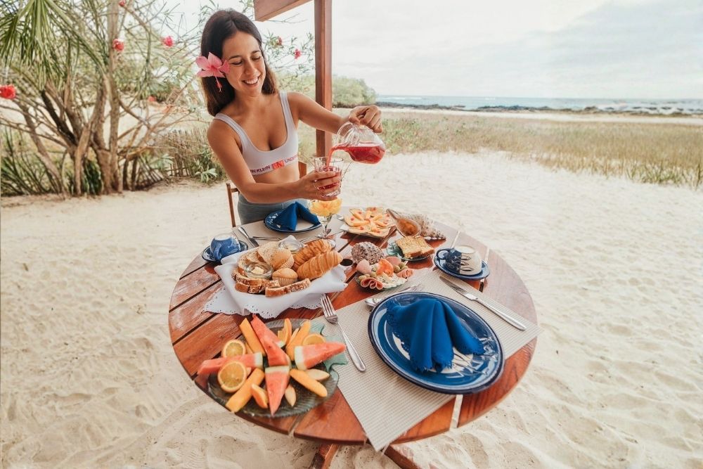 Woman enjoying beachside breakfast juice at a beachfront Galapagos restaurant in Puerto Villamil on Isabela Island