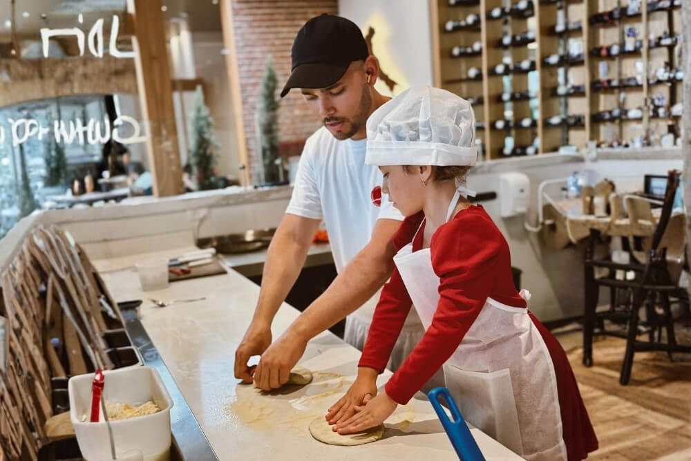 child and chef stretching pizza dough at via partenope restaurant one of the best family restaurants in quito