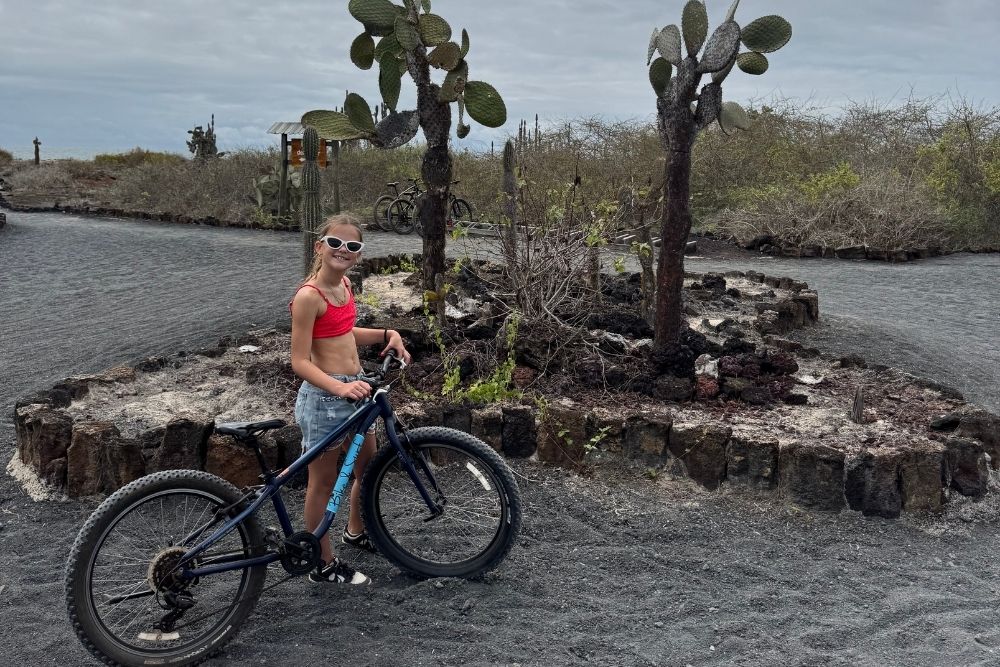 Young girl with a mountain bike standing on a volcanic dirt path on an 8 Day women Galápagos Isabela Biking tour