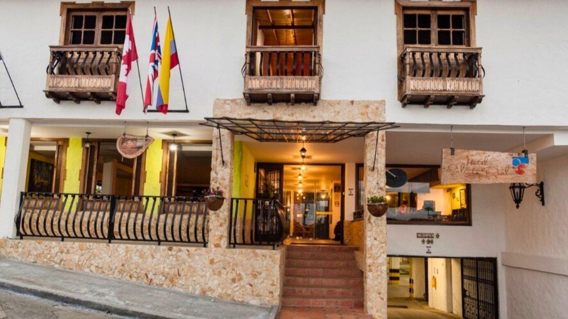Colonial facade with wooden balconies and flags at Hotel Salento Real along a sloped street in Salento Colombia