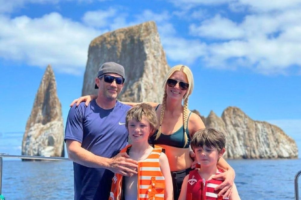 Family posing on a boat with Kicker Rock in the background during an exciting 9 day galapagos family excursion tour