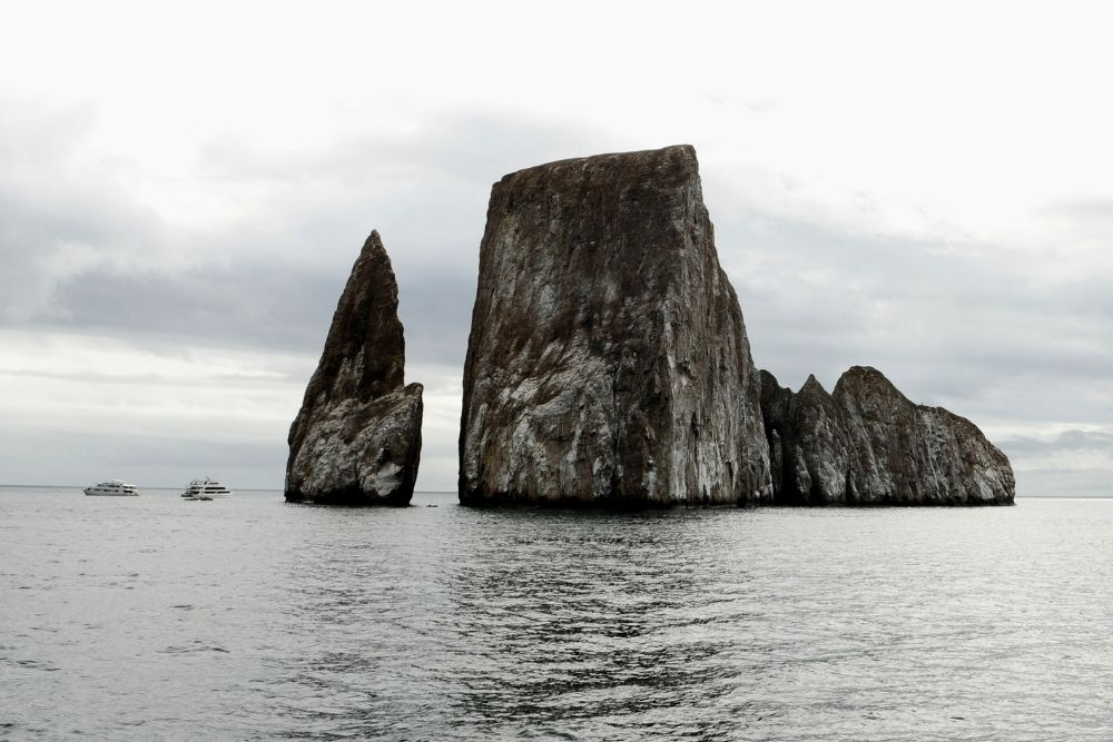 Towering rock formations of Kicker Rock rising from calm ocean waters on a 9 day luxury Ecuador trip in Galapagos