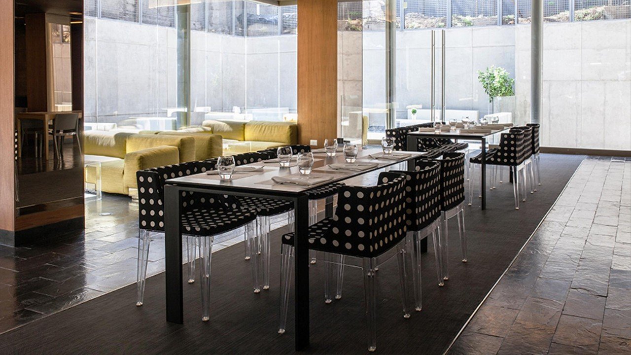 Sleek restaurant dining area with modern chairs and floor-to-ceiling windows at Solace Hotel Santiago de Chile