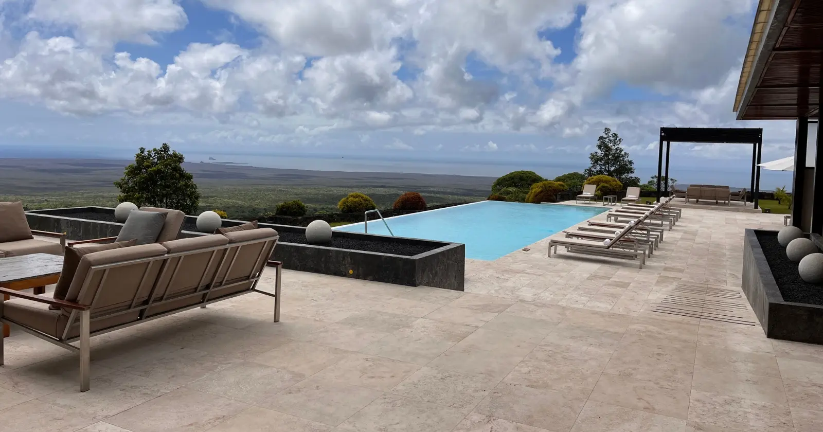 infinity pool and terrace overlooking volcanic landscape at one of the galapagos luxury hotels.