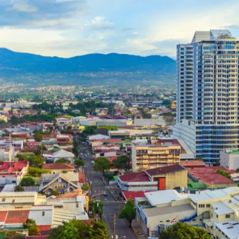 san-jose-costa-rica Rebecca Adventure Travel Panoramic urban skyline of vibrant high-rise towers and mountains in San Jose, Costa Rica under a bright blue sky