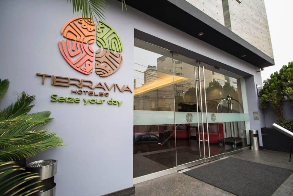 Modern entrance glass doors and Tierra Viva Hoteles logo wall at Tierra Viva Miraflores hotel in Lima Peru