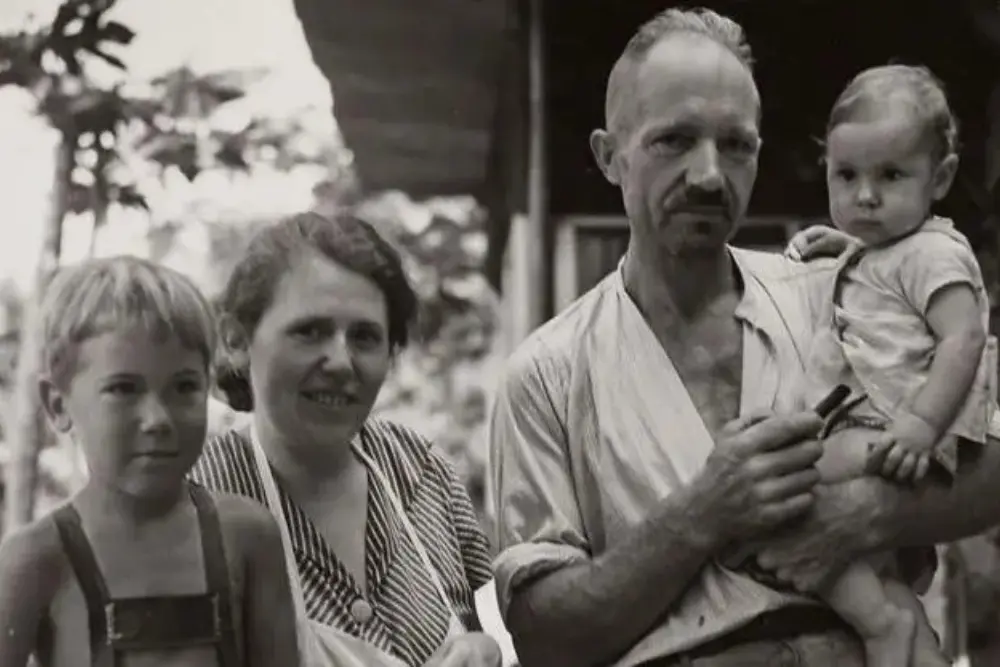 a black and white photo of the wittmers family holding tools while settling on the rugged terrain of floreana island.