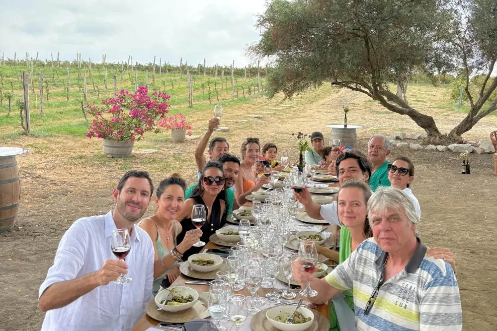 a large group toasts with wine glasses during an ecuador luxury wine experience at dos hemisferios vineyard.