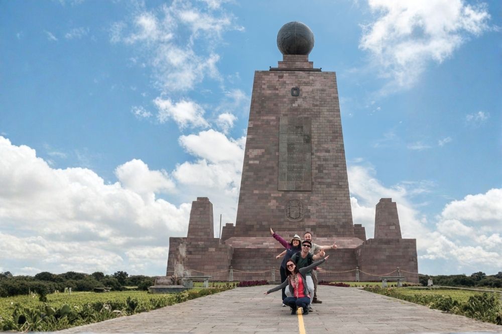 Family posing cheerfully on the equator line in front of the monument during an ecuador and galapagos family tour