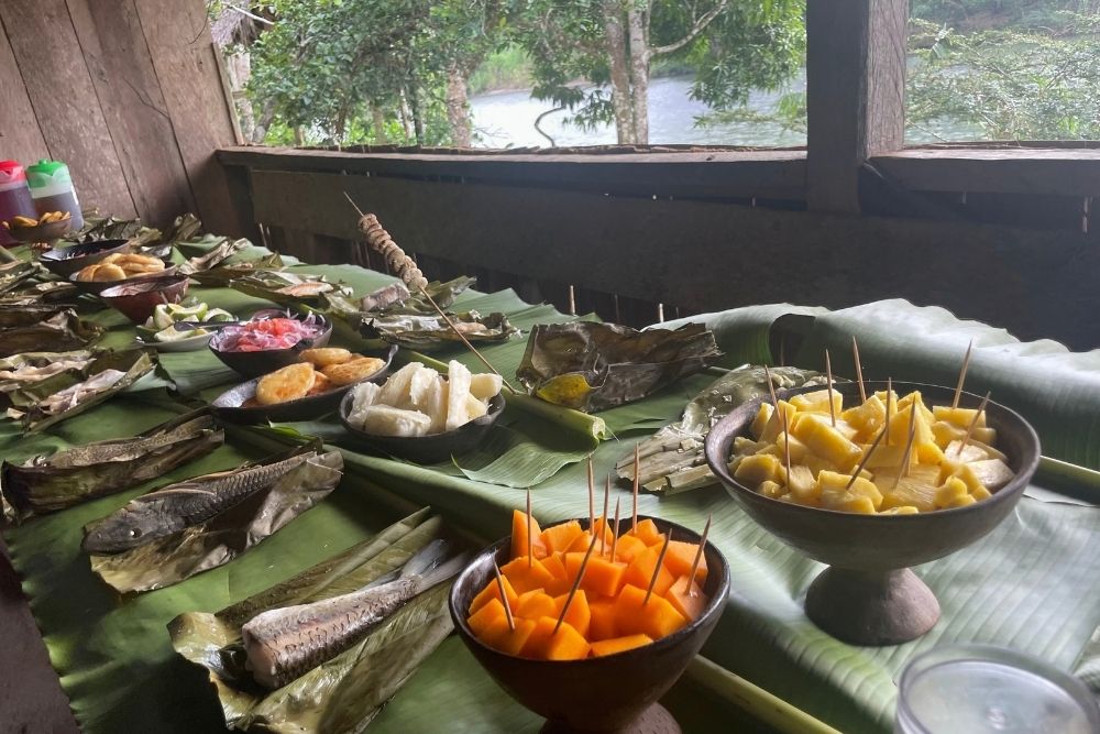 Traditional Amazonian buffet on banana leaves with tropical fruit and grilled fish in a Kichwa community in Ecuador