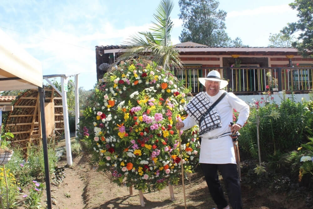 a silletero carries an elaborate floral silleta during the medellín flower festival desfile de silleteros parade, showcasing traditional antioquia craftsmanship