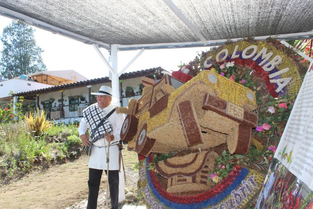 silletero poses next to silleta flower arrangement during medellin flower festival in colombia