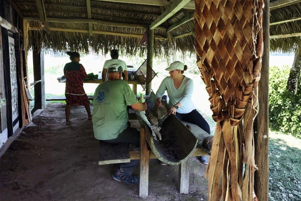 Visitors grinding cassava during an indigenous workshop with a Kichwa Community on a 15 days in Ecuador journey